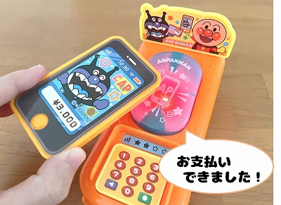 アンパンマンレジスターdxのキャッシュレス端末にスマホをかざす様子